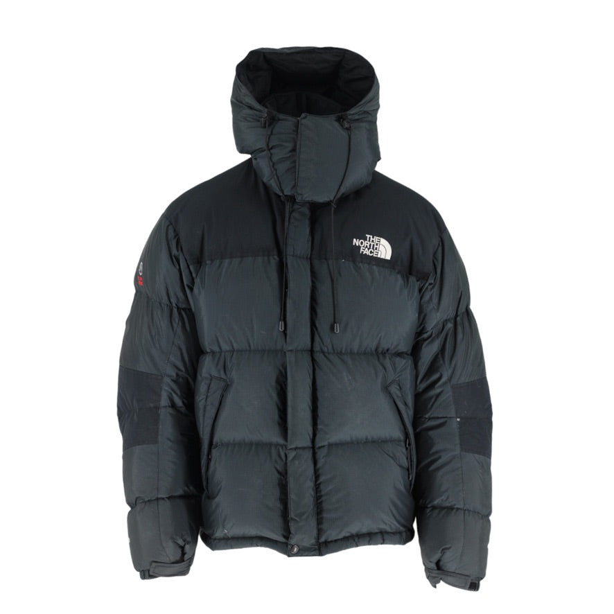 A black puffer jacket with horizontal quilting, an attached hood, and a white embroidered The North Face logo on the left chest, displayed against a solid white background.