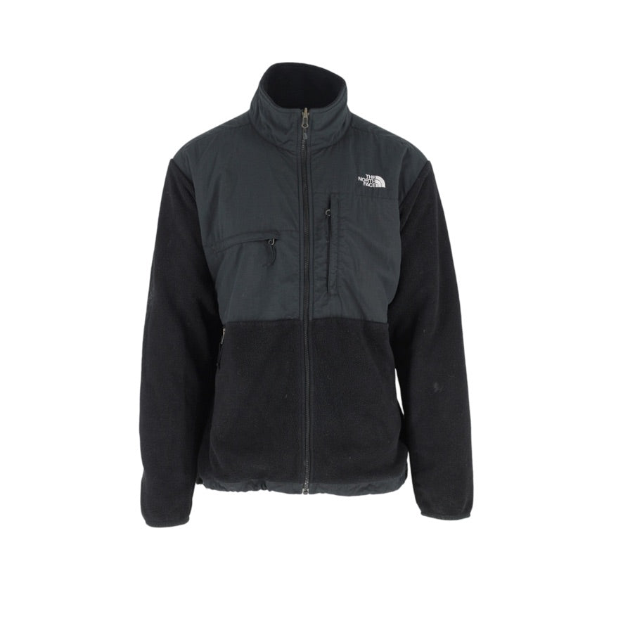 A black and dark gray colorblock fleece jacket with a full front zipper, stand-up collar, and zippered chest pocket, featuring the white embroidered 'The North Face' logo on the left chest, shown against a plain white background.
